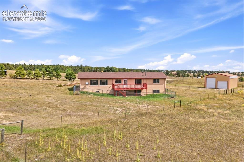 Image 50 of 50: Expansive property featuring a ranch-style residence with a red deck, a det