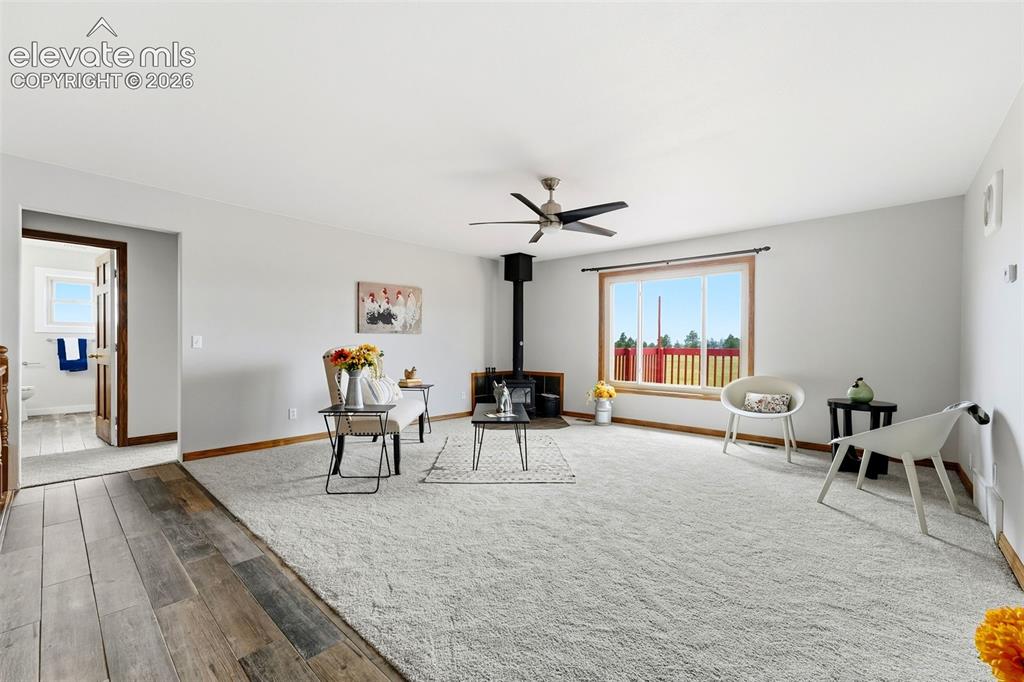 Image 6 of 50: Spacious living area featuring light-colored carpeting, a wood-burning stov