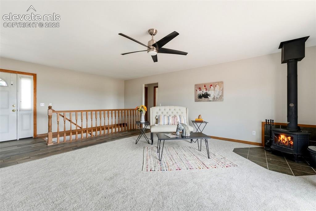 Image 7 of 50: Carpeted living space featuring a wood-burning stove with a tiled hearth, c