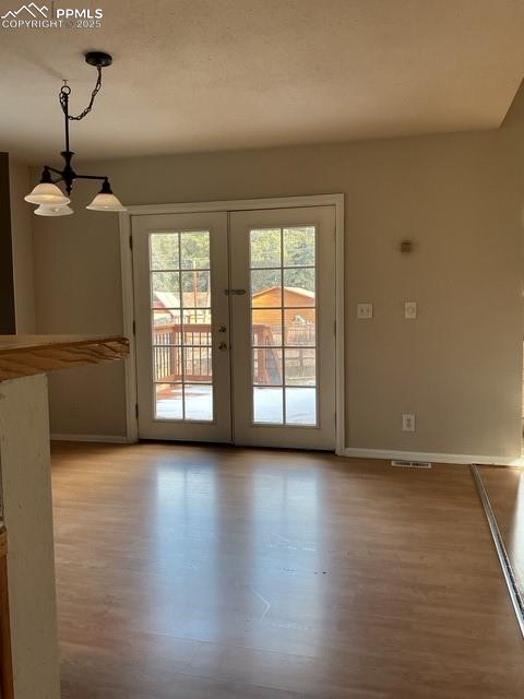 Image 17 of 30: Unfurnished dining area with french doors, light wood finished floors, and 
