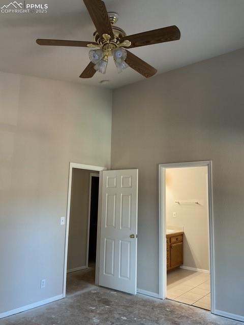 Image 23 of 30: Unfurnished bedroom with ensuite bathroom, ceiling fan, and a towering ceil