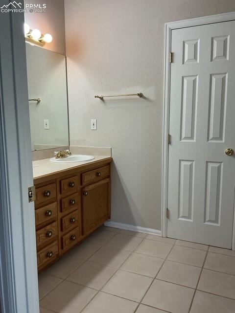 Image 24 of 30: Bathroom with vanity, light tile patterned floors, and a textured wall