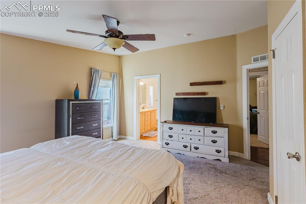 Image 11 of 30: Bedroom featuring light carpet, ceiling fan, and ensuite bathroom