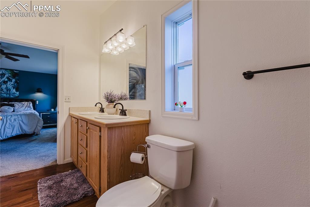 Image 14 of 30: Ensuite bathroom featuring double vanity, ceiling fan, and dark wood-style