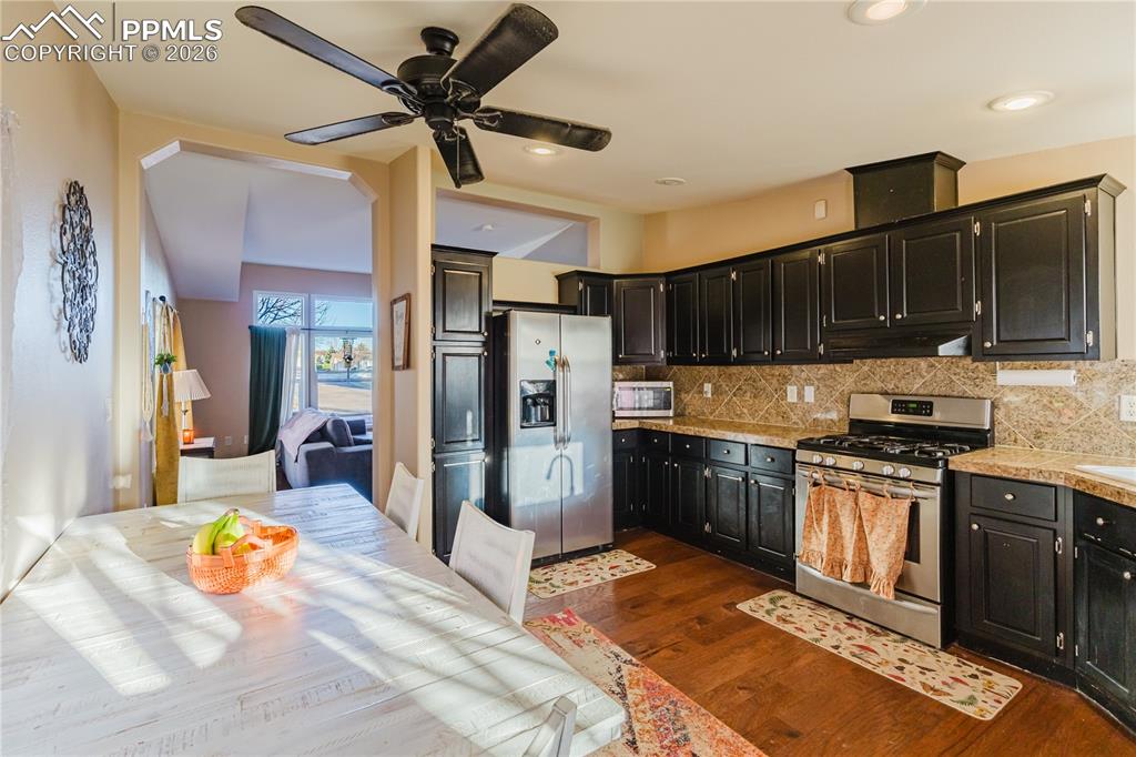Image 23 of 30: Kitchen featuring stainless steel appliances, a ceiling fan, dark wood-type