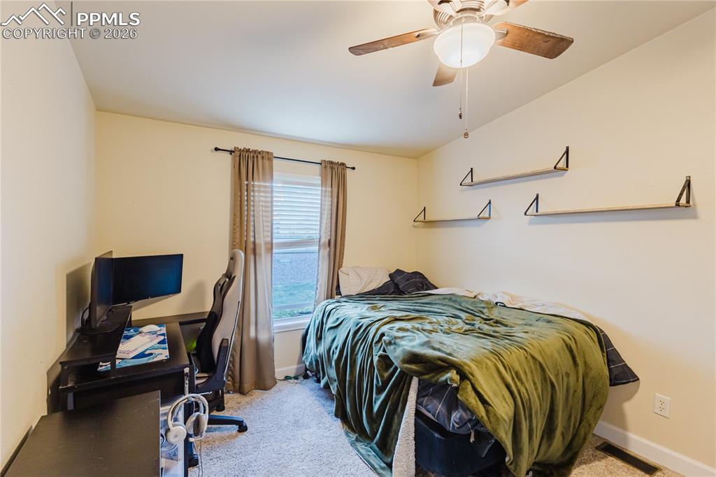 Image 7 of 30: Bedroom featuring a desk, light colored carpet, and a ceiling fan