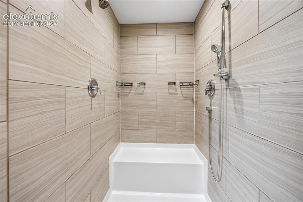 Image 24 of 49: The primary bathroom has a built in seat and dual shower heads.