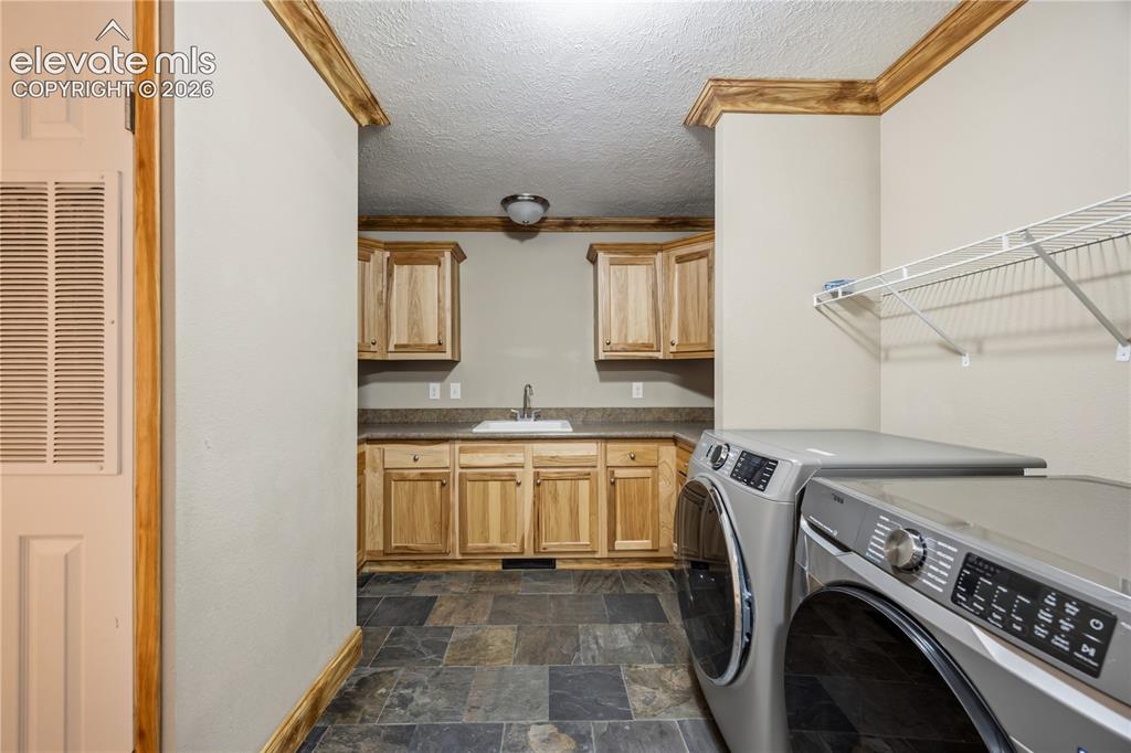 Image 37 of 49: Washer and dryer are included. Just past them is a sink and multiple cabine