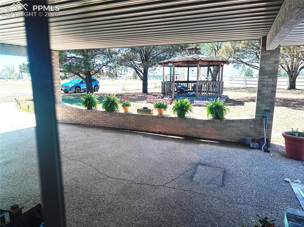 Image 11 of 48: Gazebo shown nestled in the trees west of covered entryway.