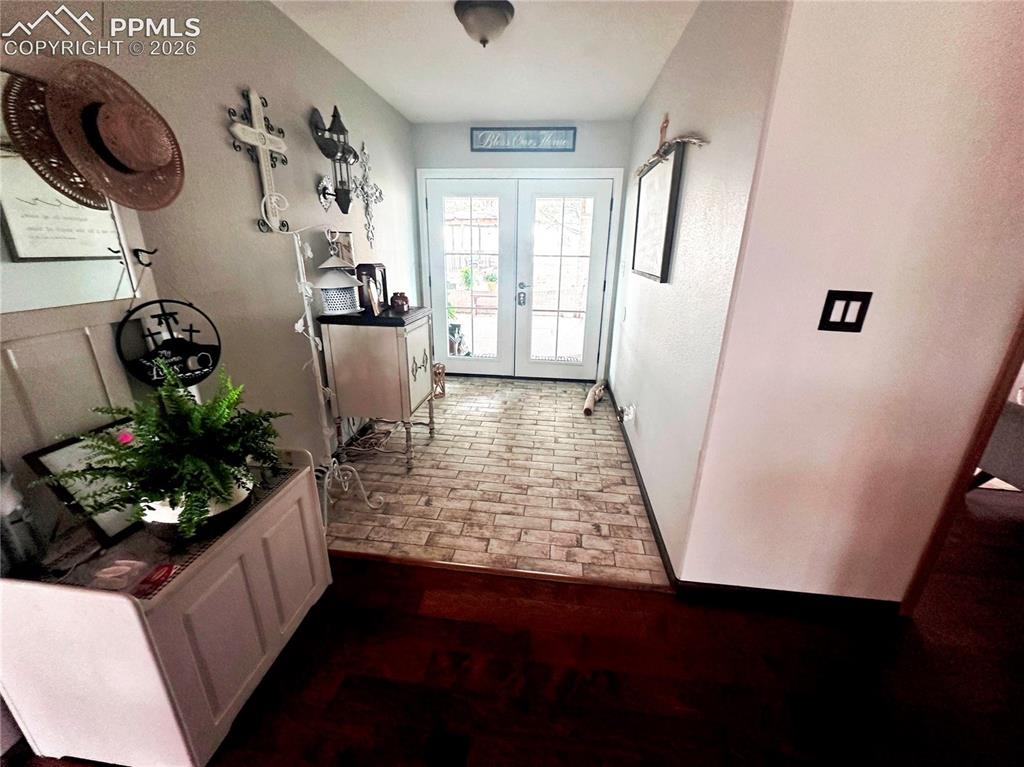 Image 13 of 48: Entrance from covered drive-under breezeway. Tiled floor joins to natural