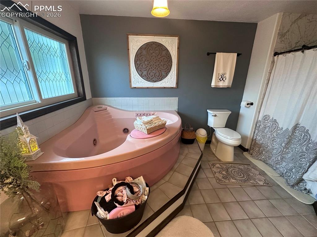 Image 32 of 48: Jetted tub, toilet and shower on the right.