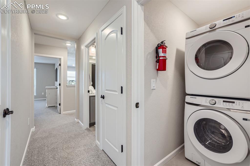 Image 15 of 16: Laundry room with light colored carpet and stacked washer / dryer