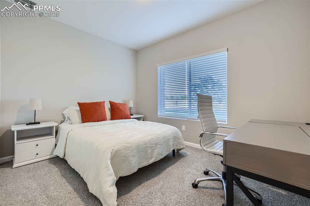 Image 4 of 16: Bedroom with light colored carpet and an office area