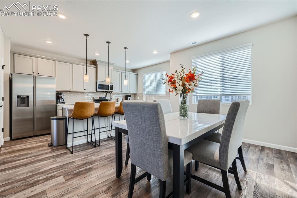 Image 7 of 16: Dining room with light wood-type flooring and recessed lighting