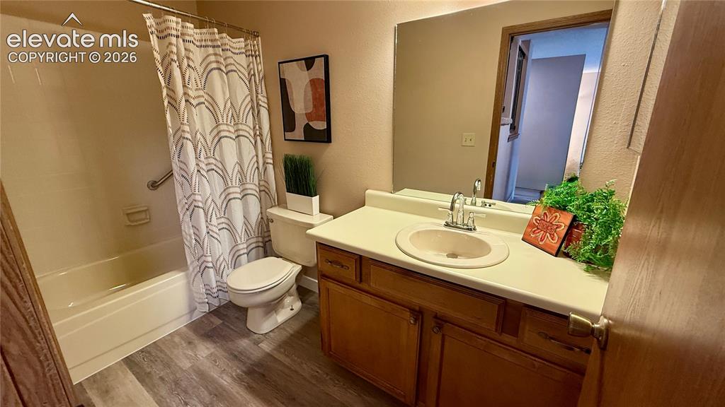 Image 12 of 26: Bathroom featuring a wood-finish vanity with a molded countertop and integr