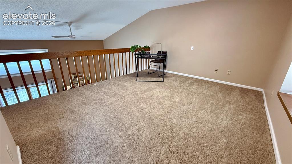Image 13 of 26: Open loft area featuring vaulted ceilings, wall-to-wall carpeting, and a wo