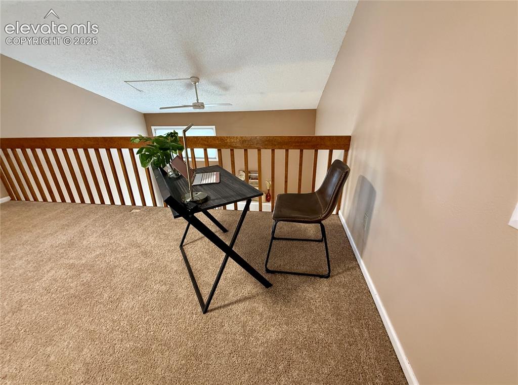 Image 14 of 26: Loft space featuring vaulted ceilings, neutral carpeting, a wooden railing,
