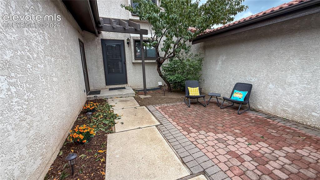 Image 2 of 26: Front gated courtyard with stucco exterior entry featuring a red brick pave