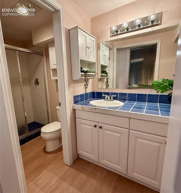 Image 20 of 26: Bathroom featuring a vanity with white cabinetry, a tile countertop, a sink