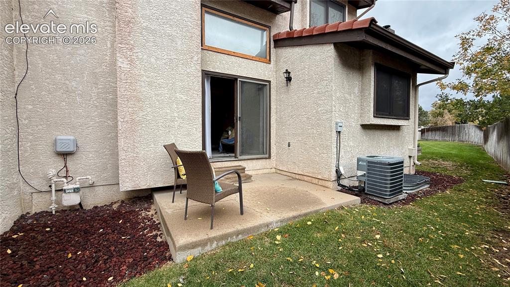 Image 22 of 26: Stucco exterior featuring a concrete patio, sliding glass door, fixed upper