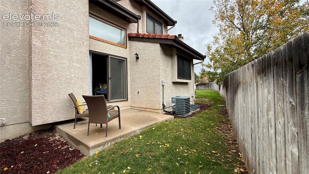 Image 23 of 26: Stucco exterior featuring a concrete patio, wood-style privacy fencing, and
