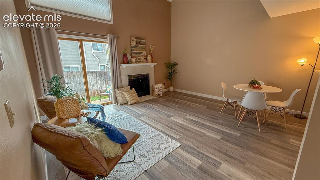 Image 3 of 26: Vaulted ceilings with upper window, wood-look flooring, fireplace with whit