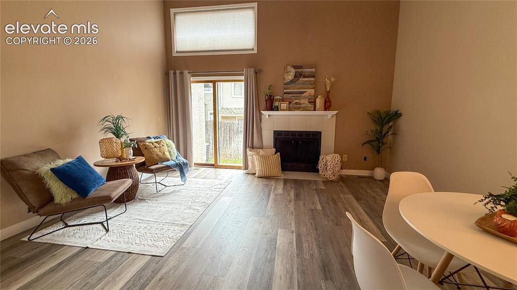 Image 4 of 26: High-ceilinged living area featuring wood-look flooring, a masonry fireplac