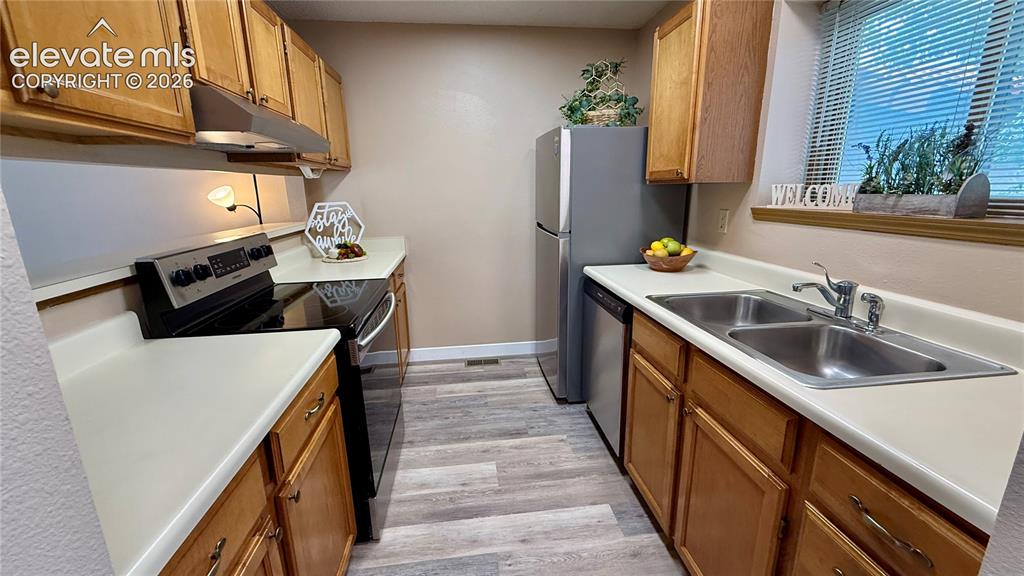 Image 6 of 26: Kitchen featuring wood cabinetry, light colored countertops, wood-look floo