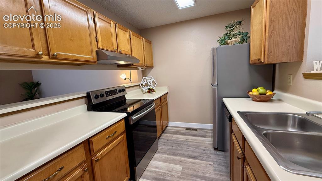 Image 7 of 26: Kitchen featuring wood-look cabinetry, light colored countertops, wood-look