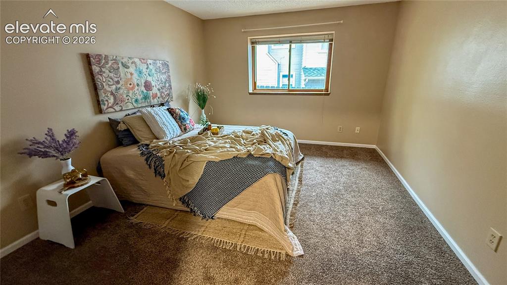 Image 8 of 26: Main level bedroom with neutral wall coloring, wall-to-wall carpeting, and