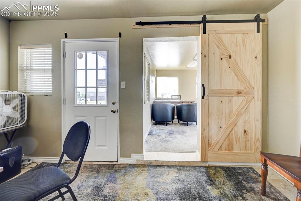 Image 19 of 42: Carpeted entryway with a barn door and baseboards