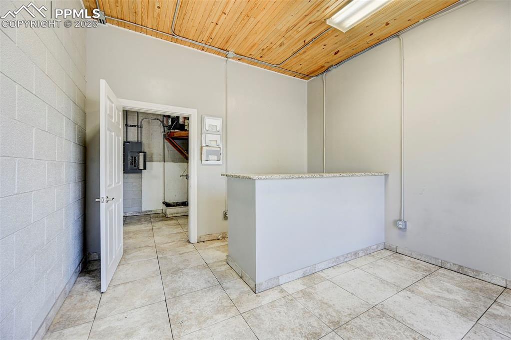 Image 21 of 42: Empty room featuring wooden ceiling, light tile patterned flooring, and ele