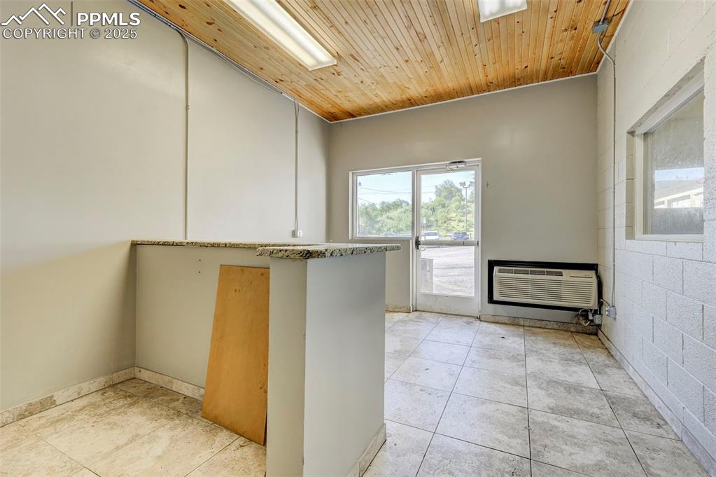 Image 26 of 42: Kitchen featuring a wall unit AC, light tile patterned flooring, and wood c