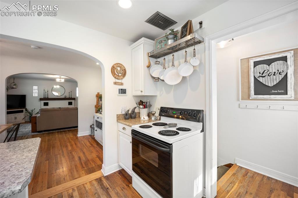Image 12 of 47: Kitchen with white range with electric stovetop, arched walkways, light cou