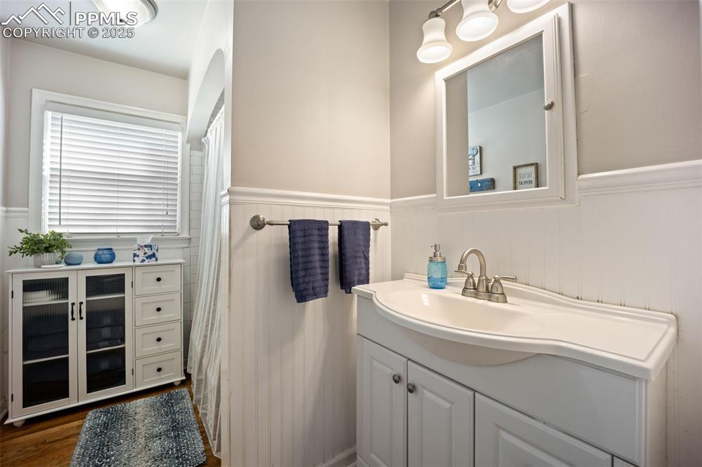 Image 15 of 47: Full bath featuring vanity, wainscoting, a shower with curtain, and wood fi