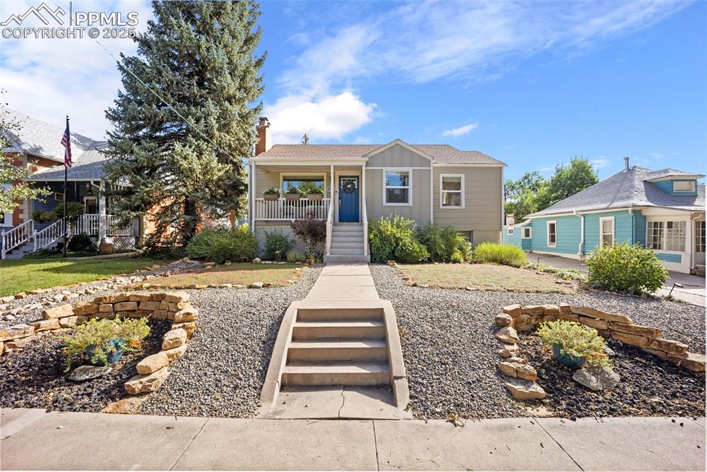 Image 2 of 47: View of front of home featuring stairway, covered porch, a chimney, and roo