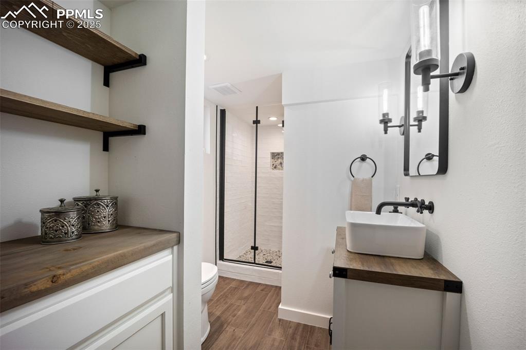 Image 23 of 47: Bathroom featuring vanity, a stall shower, and wood finished floors