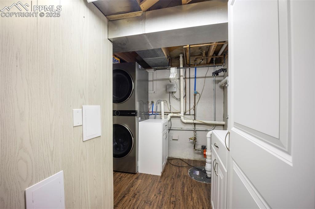 Image 29 of 47: Laundry room featuring stacked washing machine and dryer and dark wood-styl