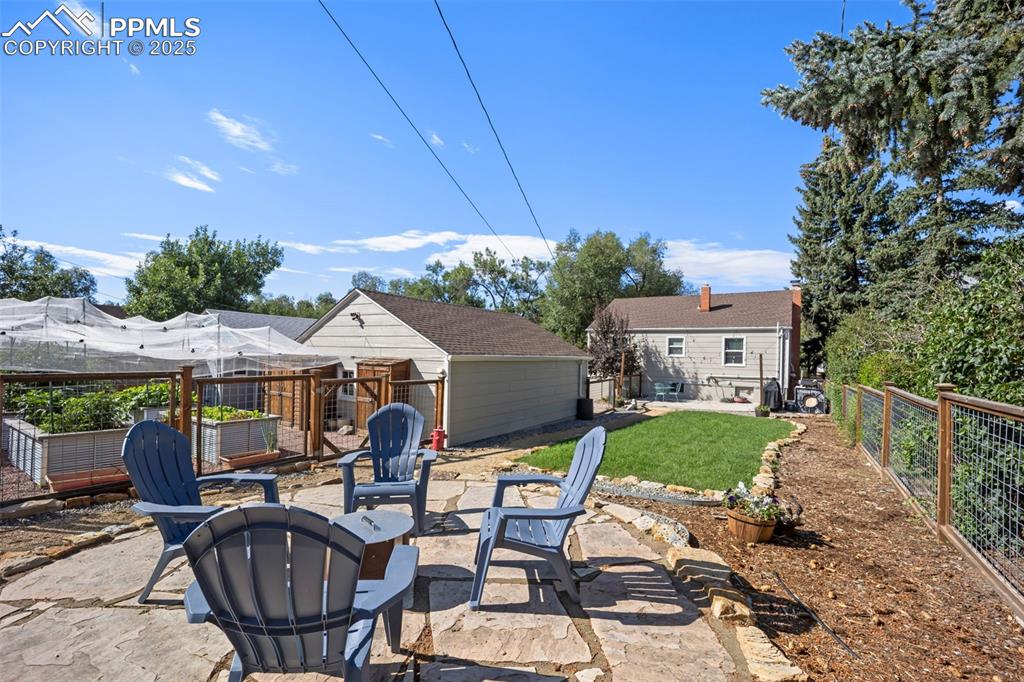 Image 33 of 47: Fenced backyard featuring a patio area, a fire pit, an outbuilding, and a g