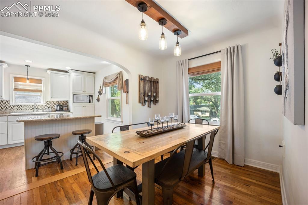 Image 7 of 47: Dining space with arched walkways, wood-type flooring, and healthy amount o