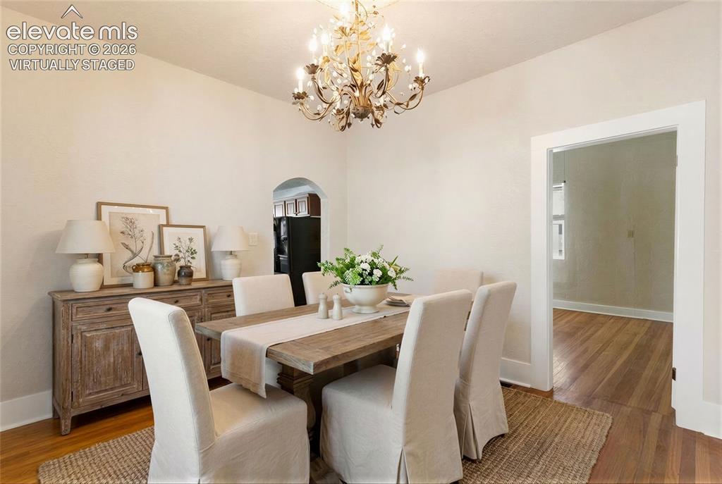 Image 16 of 42: Virtually Staged Hardwood flooring, chandelier lighting, and a wide cased o