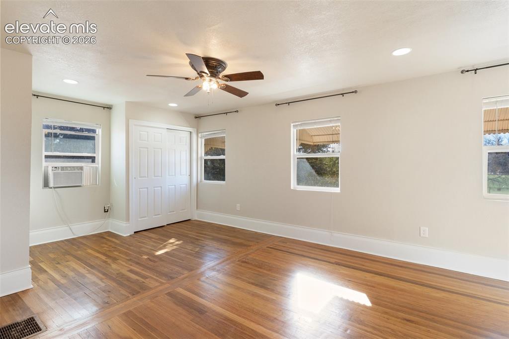 Image 32 of 42: Hardwood flooring throughout, featuring a ceiling fan with integrated light