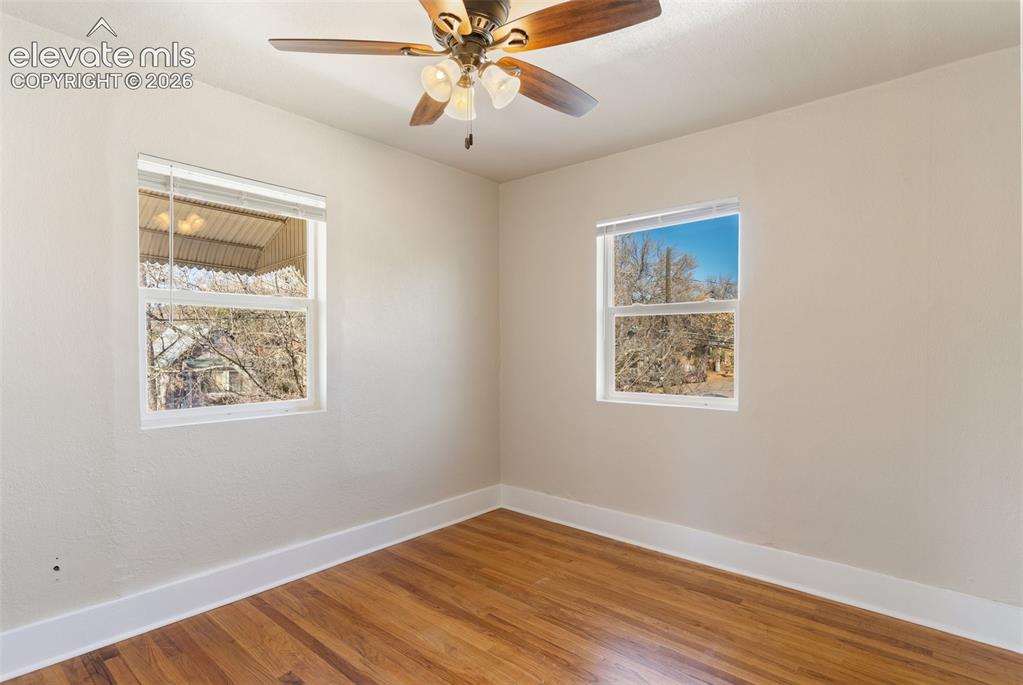 Image 34 of 42: Wood-finish flooring, white walls, and a ceiling fan with light fixture