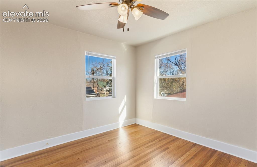 Image 36 of 42: Hardwood flooring, two windows, and a ceiling fan with integrated lighting