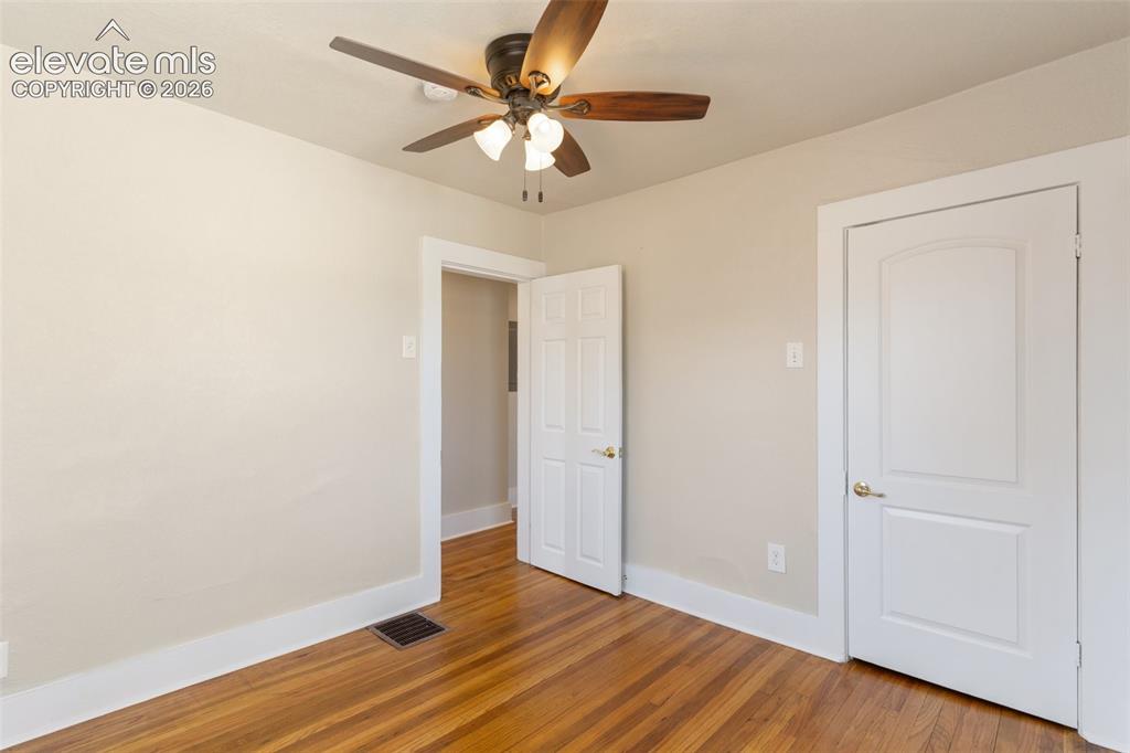 Image 37 of 42: Hardwood flooring, ceiling fan, white trim, and a paneled door