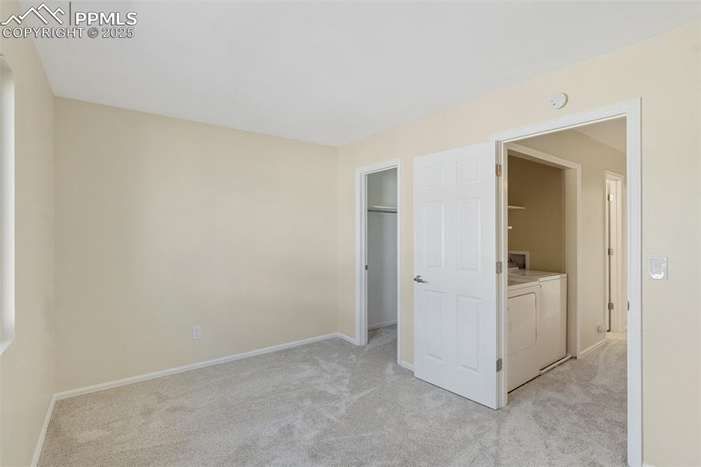 Image 11 of 26: Unfurnished bedroom featuring light carpet, washing machine and clothes dry