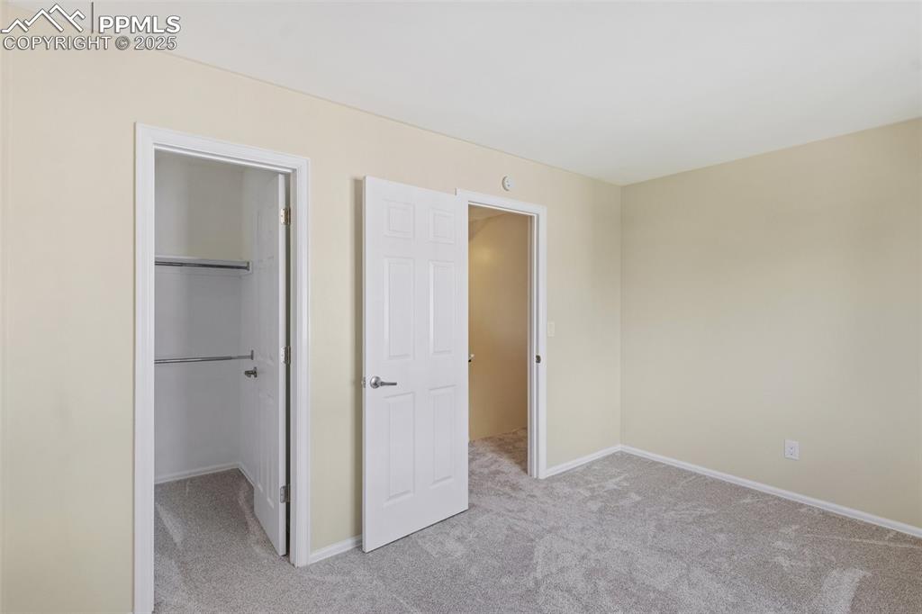 Image 12 of 26: Unfurnished bedroom featuring light carpet and a walk in closet