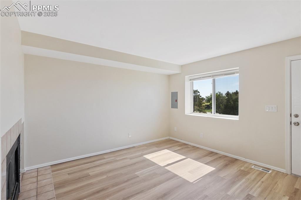 Image 3 of 26: Unfurnished living room with a fireplace with flush hearth, light wood-styl