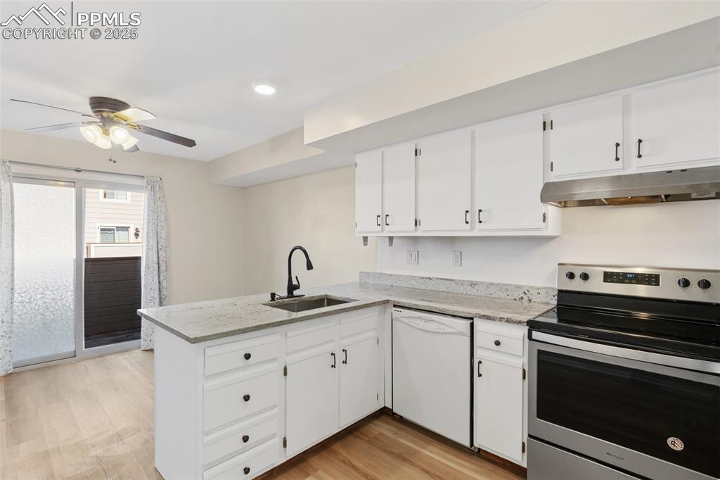 Image 6 of 26: Kitchen with electric range, a peninsula, under cabinet range hood, light w