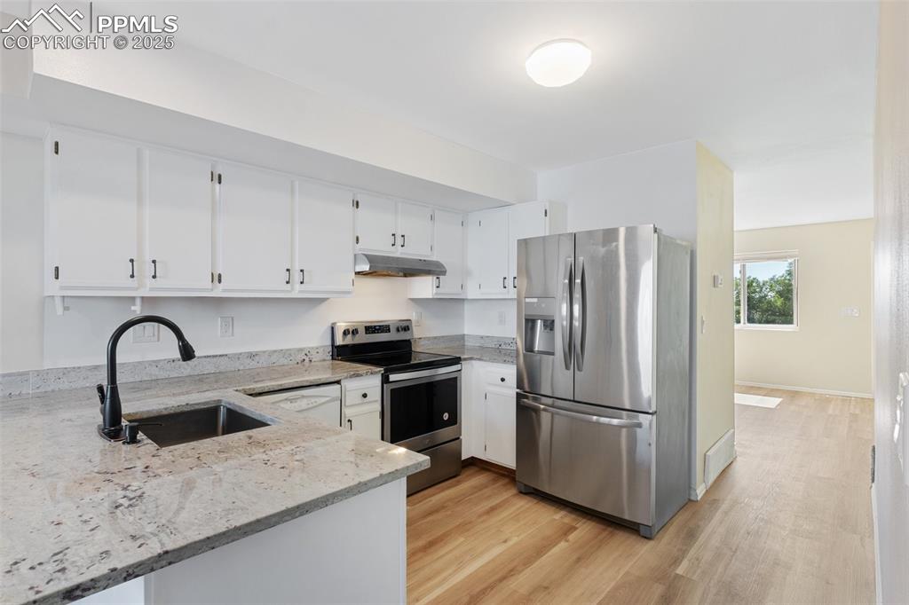 Image 7 of 26: Kitchen featuring stainless steel appliances, light stone counters, light w